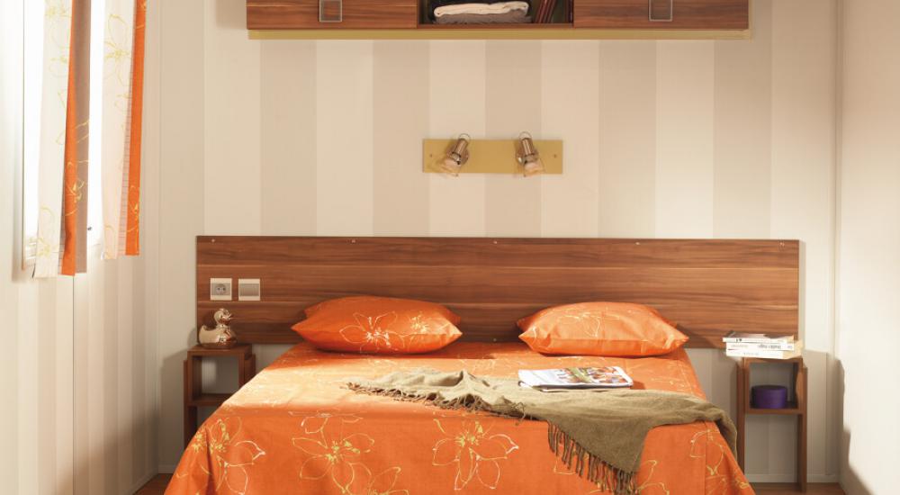 Une chambre avec un lit double en 140 x 190 équipées d'espaces de rangement.
